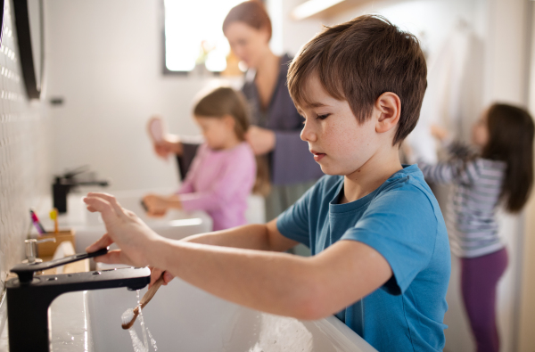 A mother with three little children in bathroom, morning routine concept.