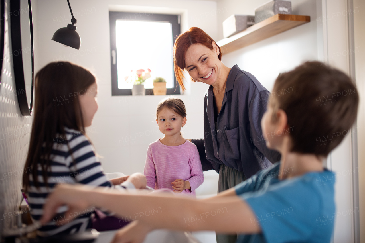 A mother with three little children in bathroom, morning routine concept.