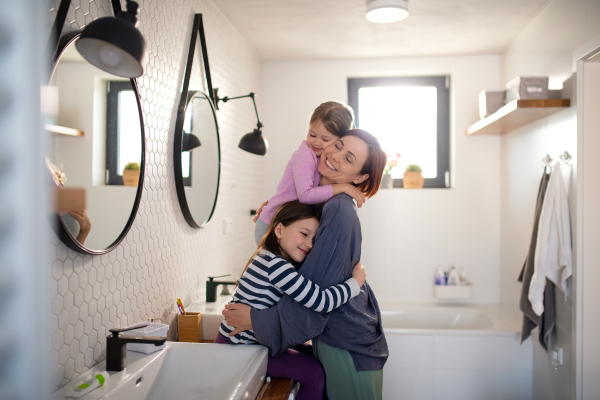 A mother hugging her little children in bathroom at home.