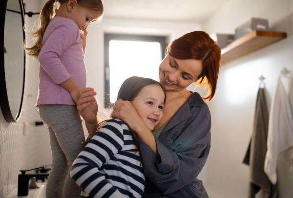 A mother hugging her little daughter in bathroom at home.