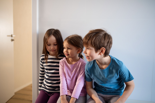 The three little children siblings sitting at home.