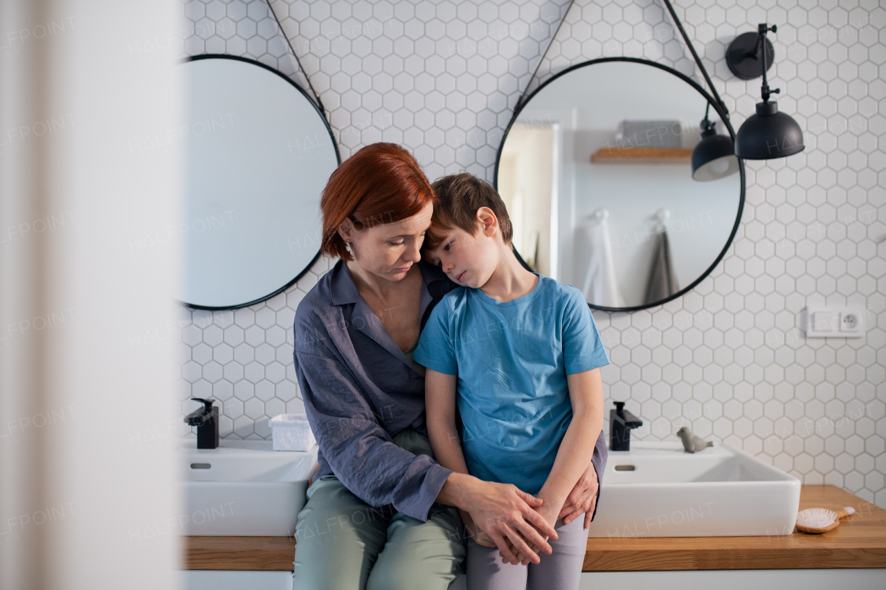 A mother hugging and consoling little boy in bathroom at home.