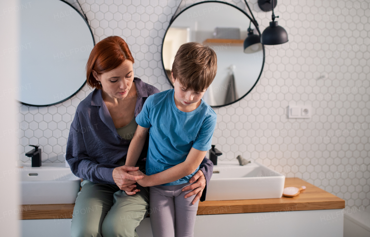 A mother consoling her little upset son in bathroom at home.