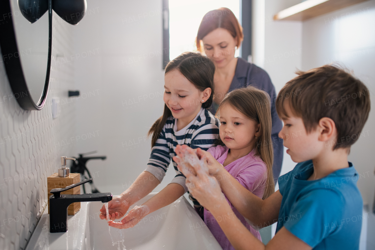 A mother supervising three little children in bathroom, morning routine concept.