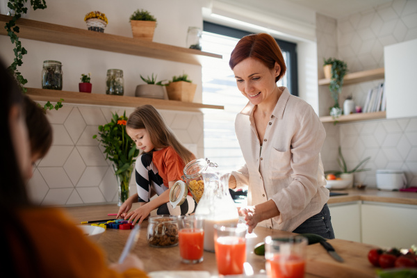 A mother of three little children preparing breakfast in kitchen at home.