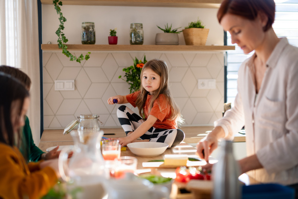 A mother of three little children preparing breakfast in kitchen at home.