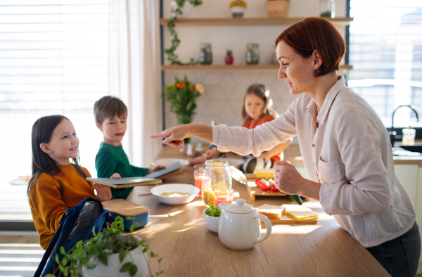 A mother of three little children preparing breakfast in kitchen at home.