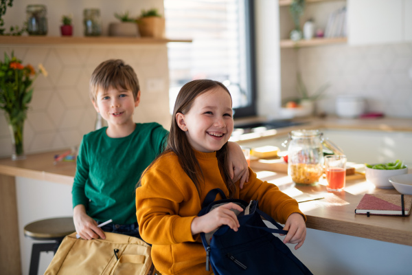 Little children packing to school in the morning in kitchen.