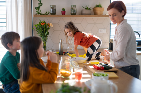 A mother of three little children preparing breakfast in kitchen at home.