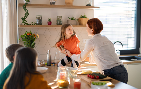 A mother of three little children preparing breakfast in kitchen at home.