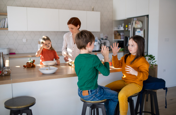 A mother of three little children preparing breakfast in kitchen at home.