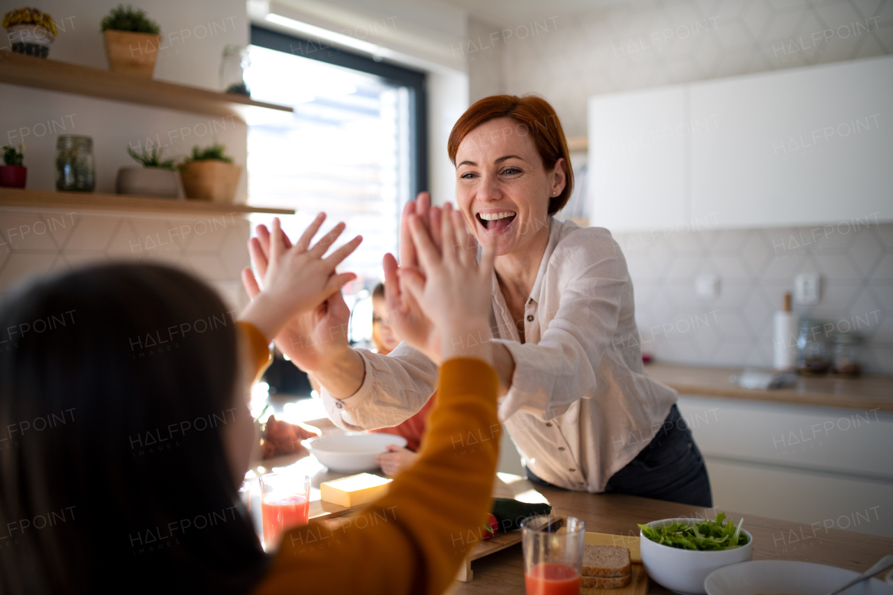 A happy mother of three little children preparing lunch boxes in kitchen at home.