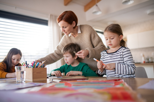 A mother of three little children supervising them when diong homework at home.