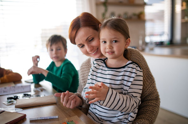 A mother of three little children supervising them when diong homework at home.