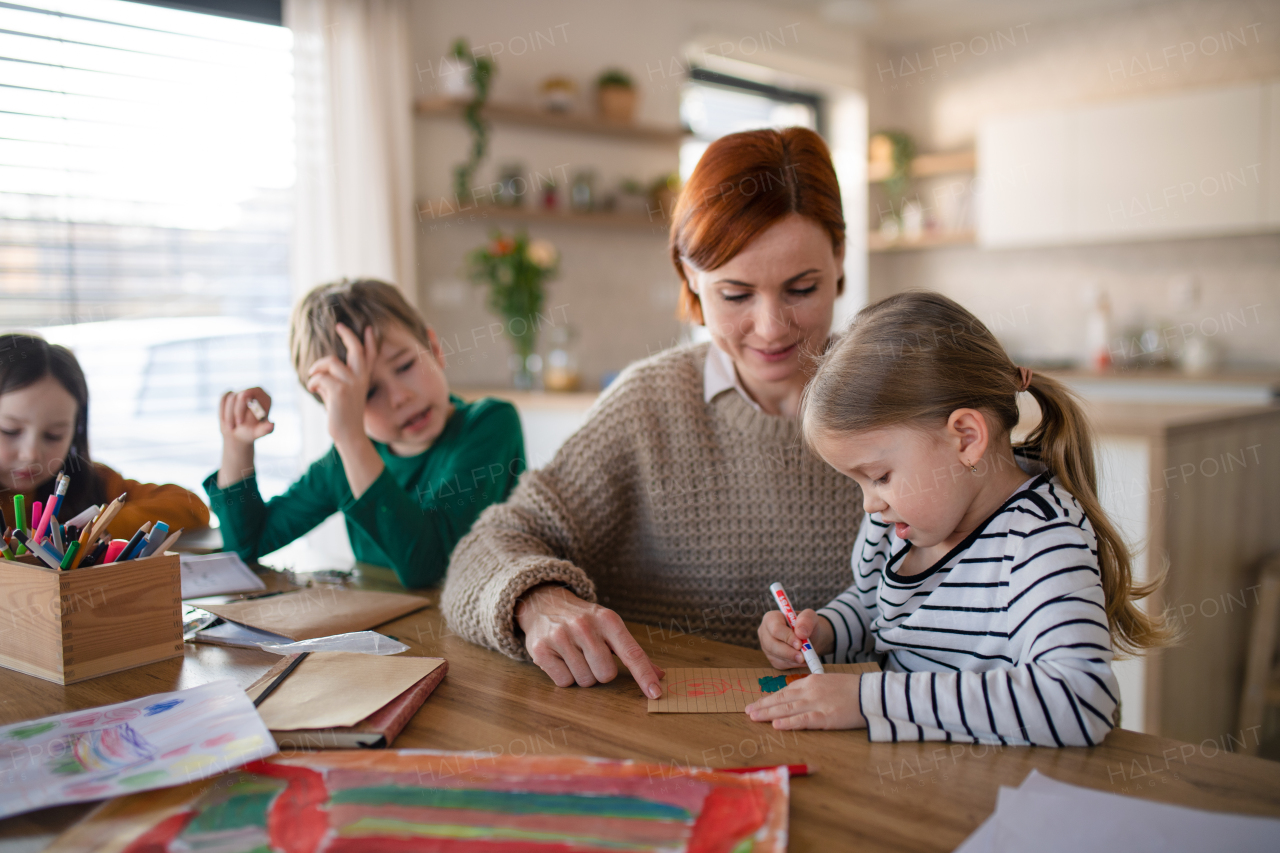 A mother of three little children supervising them when diong homework at home.