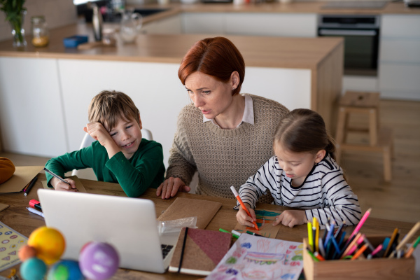 A mother of little children supervising them when distance learning and doing artwork at home.