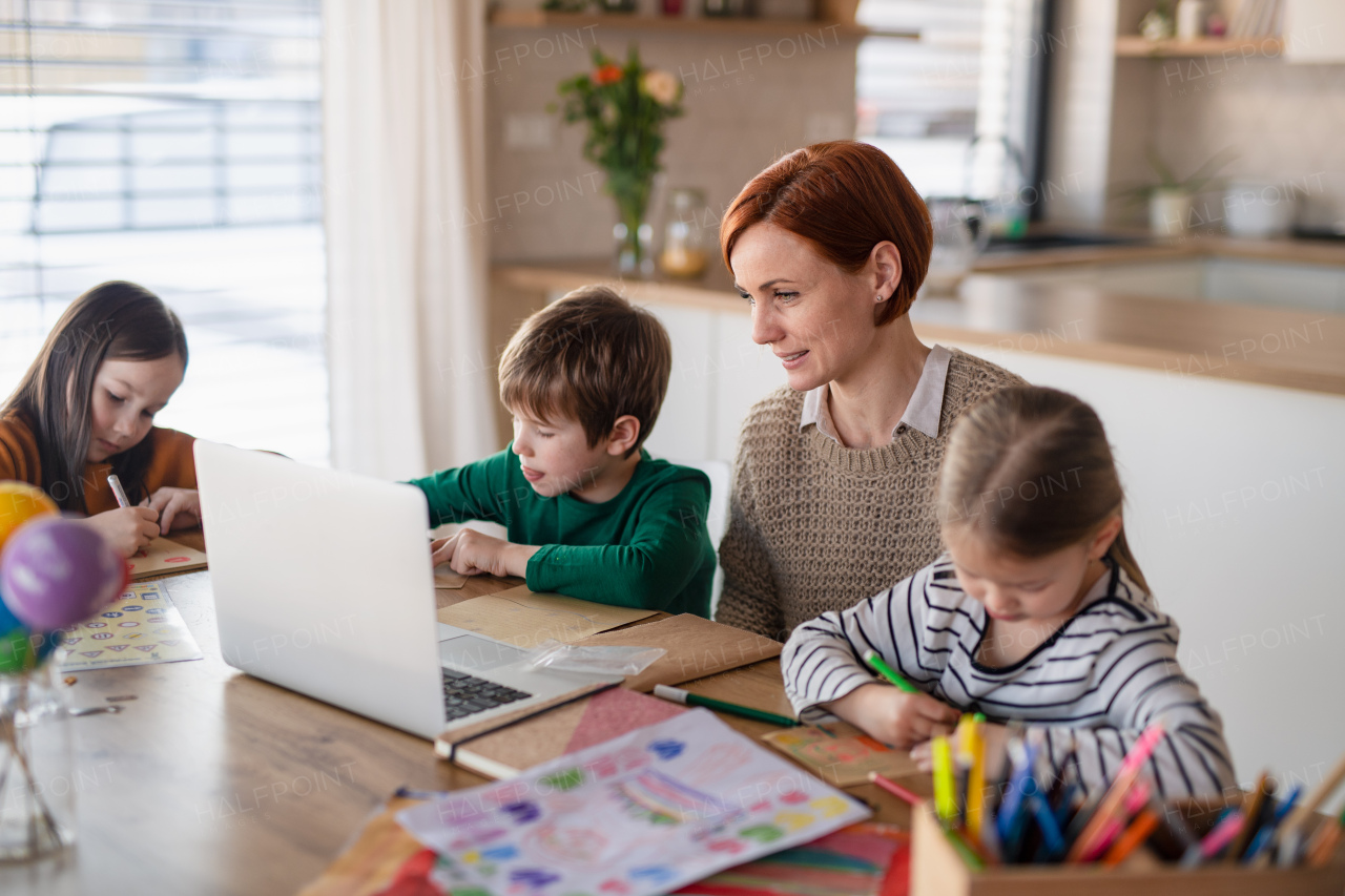 A mother of little children supervising them when distance learning and doing homework at home.