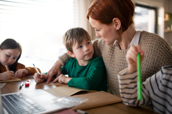 A mother of three little children supervising them when diong homework at home.