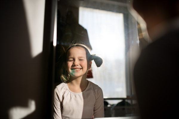 A little girl with blue stain on her face smiling with eyes closed at home.