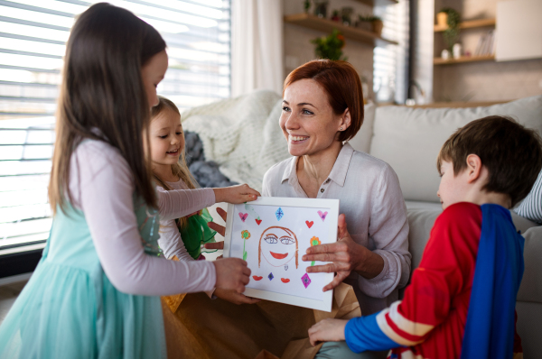 A mother of little children in costumes getting present from them at home.