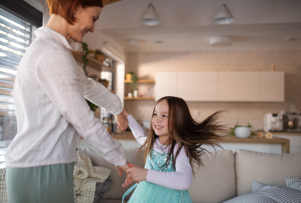 A happy mother having fun with little daughter in princess costume at home.