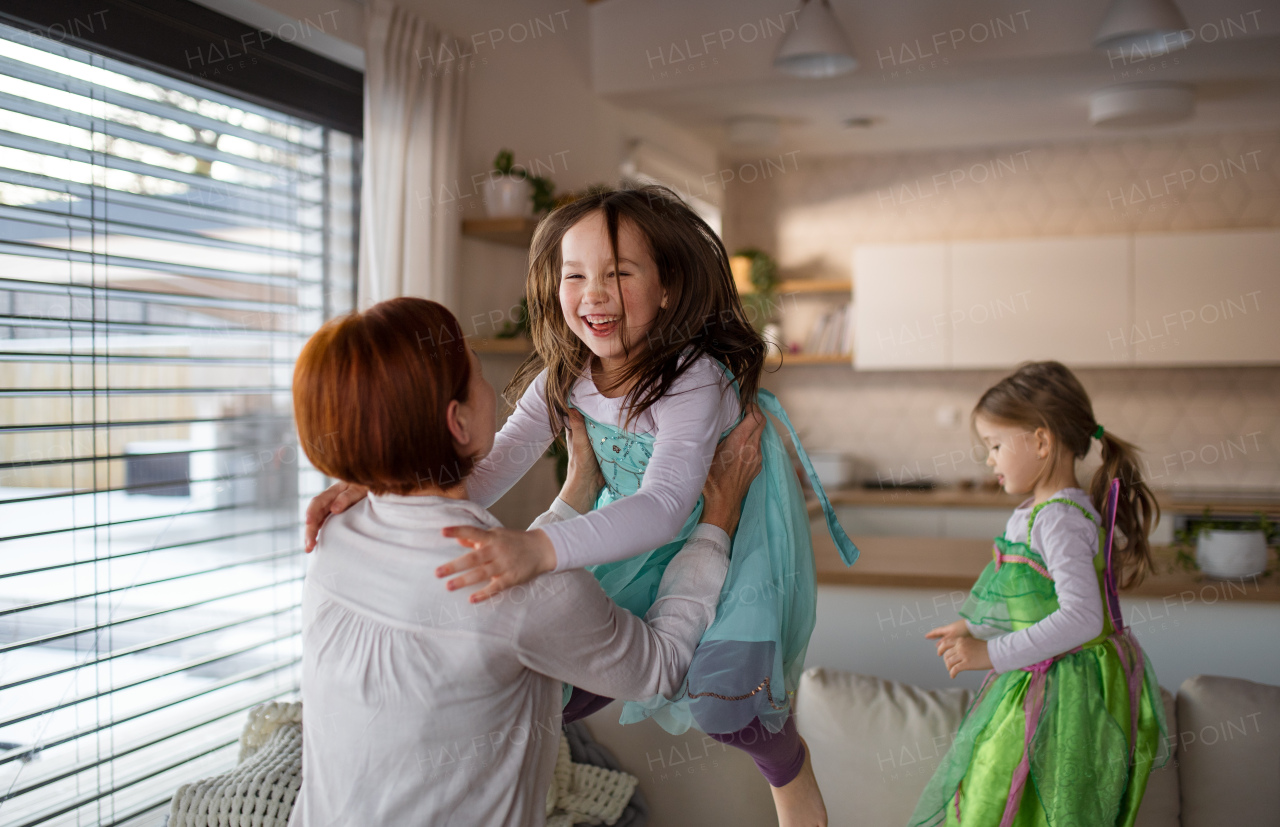 A happy mother having fun with little daughter in princess costumes at home.