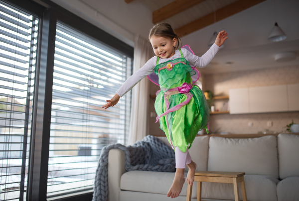 A little girl in fairy costume playing at home.