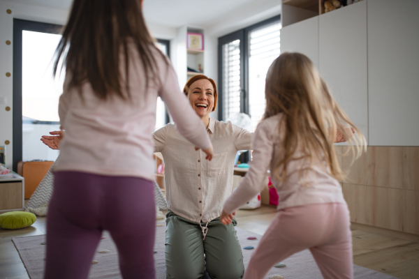 A cheerful mother of little children receiving hugs from them at home.