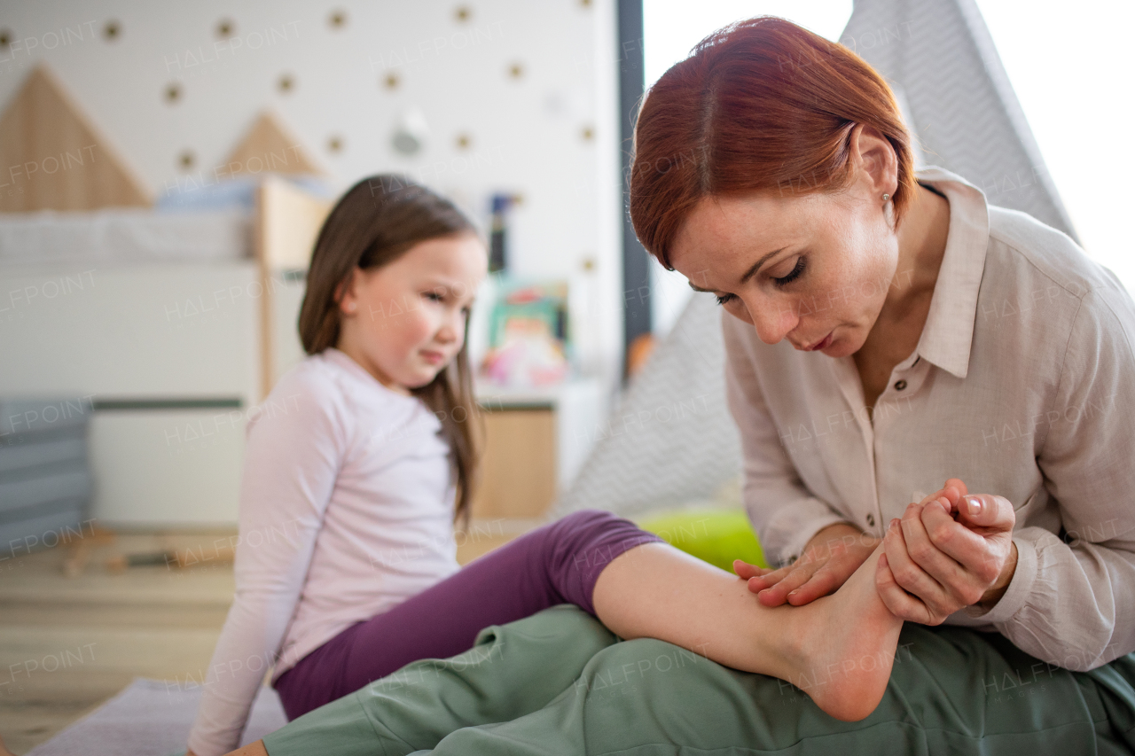 A mother blowing her little daughter's hurt ankle.