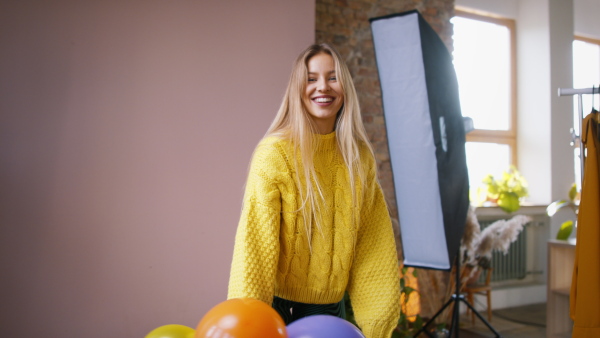 A fashion studio shooting of a happy young woman with balloons , backstage of photoshooting .