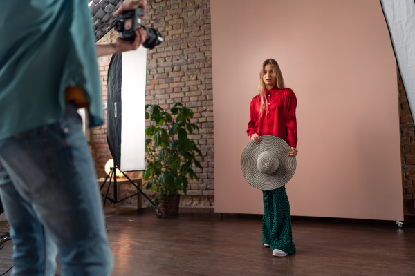 A young photographer taking picures of model, backstage of photoshooting in studio.