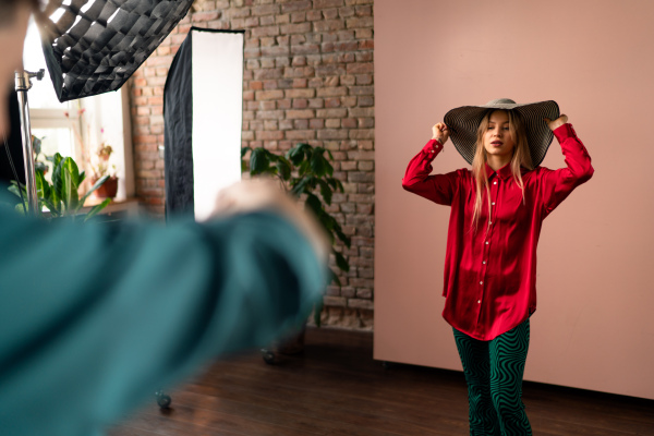 A young photographer taking picures of model, backstage of photoshooting in studio.