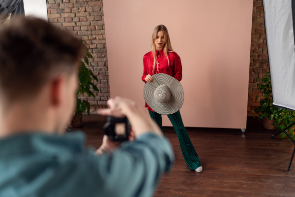 A young photographer taking picures of model, backstage of photoshooting in studio.