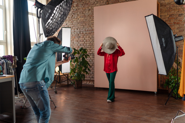 A young photographer taking picures of model, backstage of photoshooting in studio.