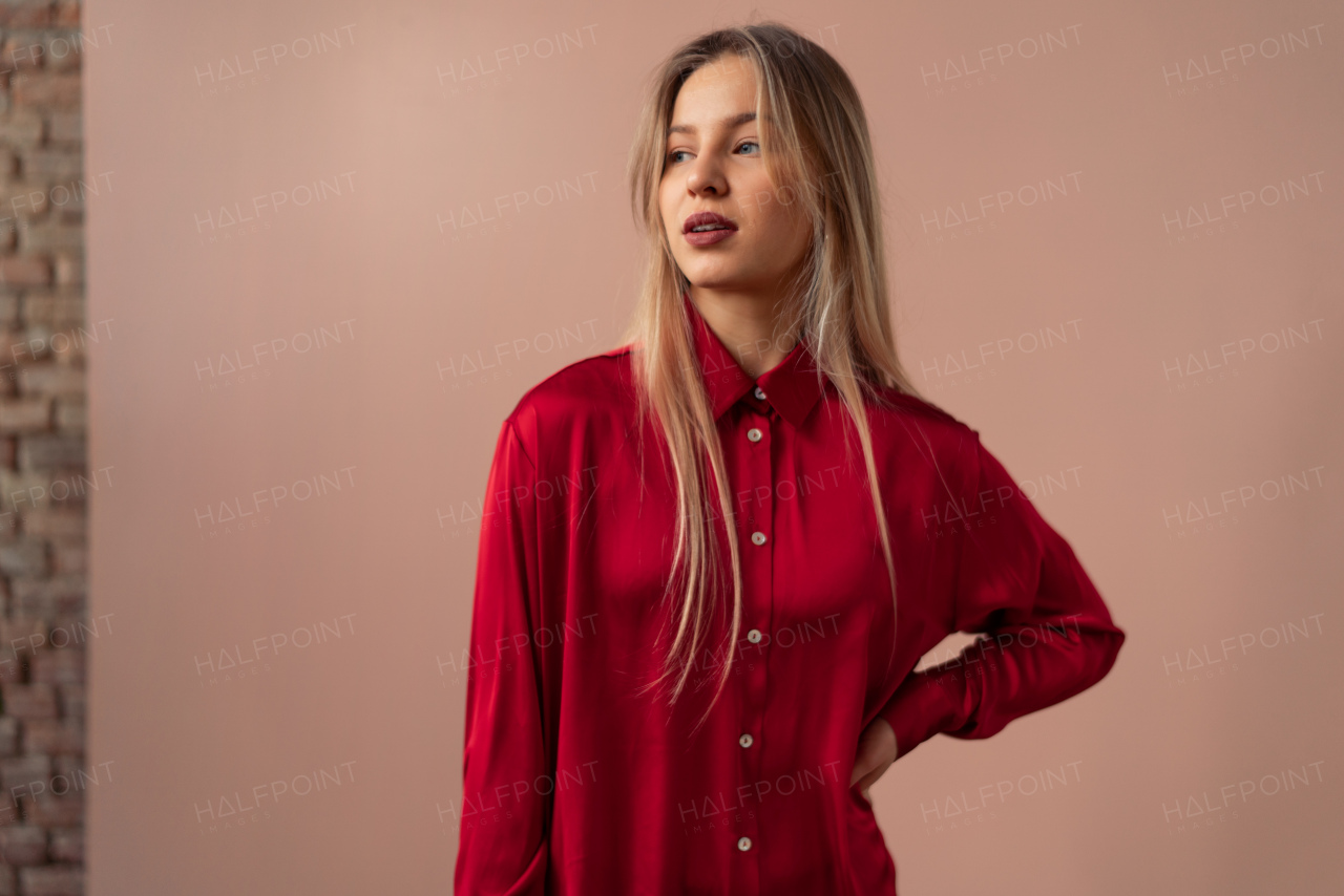 Fashion studio portrait of a young blonde woman posing over pink background.