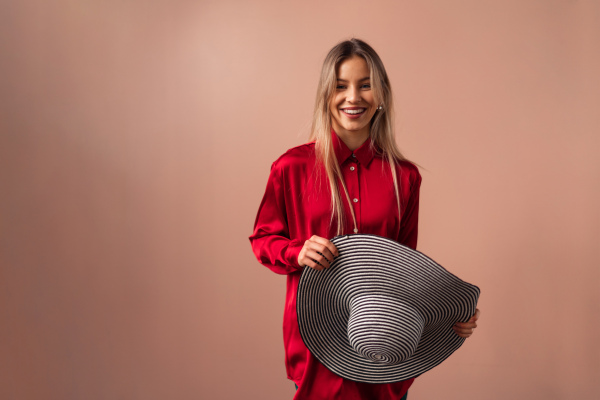 Fashion studio portrait of a young blonde woman posing over pink background.