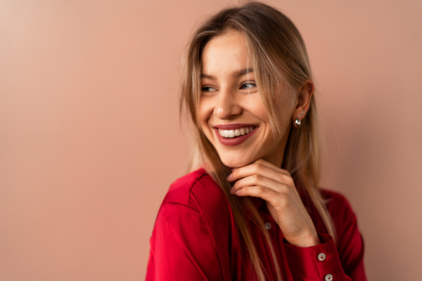 Fashion studio portrait of happy young blonde woman posing over pink background.