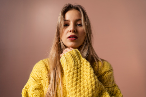 Fashion studio portrait of a young blonde woman posing over pink background.