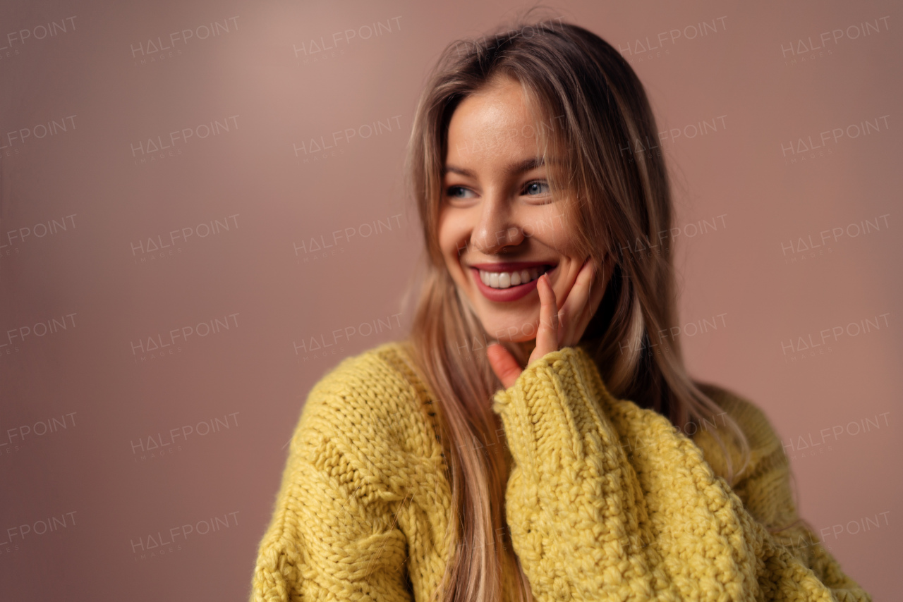 Fashion studio portrait of a young blonde woman posing over pink background.