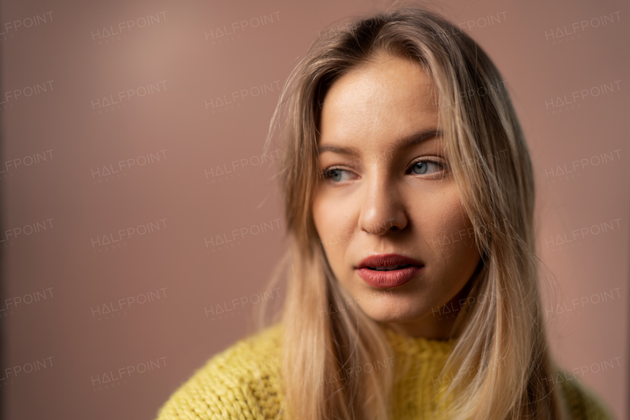 Fashion studio portrait of a young blonde woman posing over pink background.