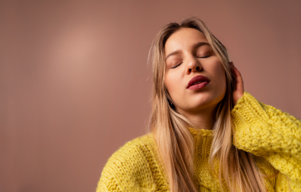 Fashion studio portrait of a young blonde woman posing over pink background.