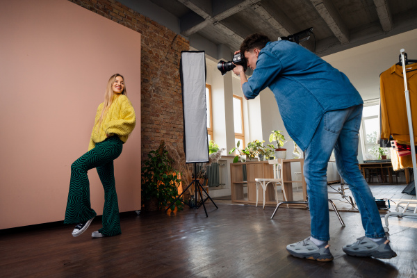 A young photographer taking picures of model, backstage of photoshooting in studio.