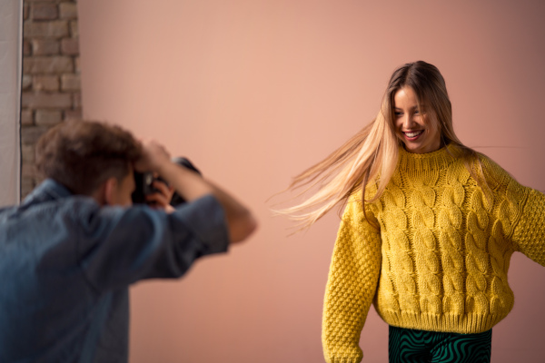 A young photographer taking picures of model, backstage of photoshooting in studio.