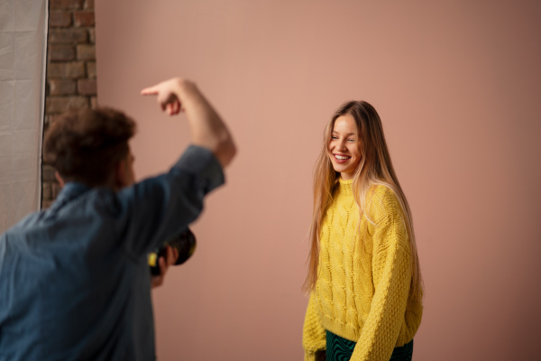 A young photographer taking picures of model, backstage of photoshooting in studio.