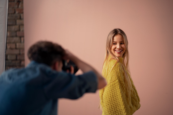 A young photographer taking picures of model, backstage of photoshooting in studio.