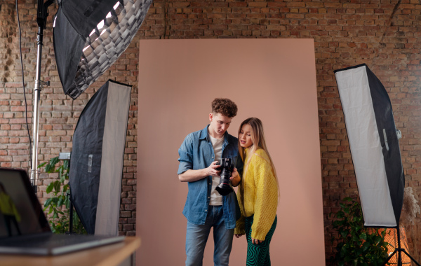 A young photographer showing picures to model, backstage of photoshooting in studio.