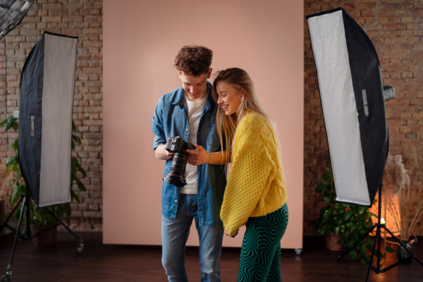 A young photographer showing picures to model, backstage of photoshooting in studio.