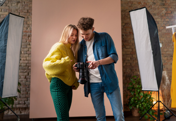 A young photographer showing picures to model, backstage of photoshooting in studio.