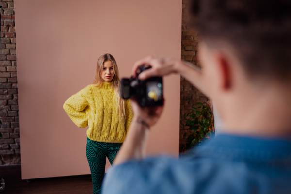 A young photographer taking picures of model, backstage of photoshooting in studio.