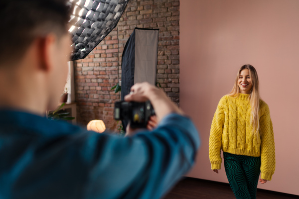 A young photographer taking picures of model, backstage of photoshooting in studio.